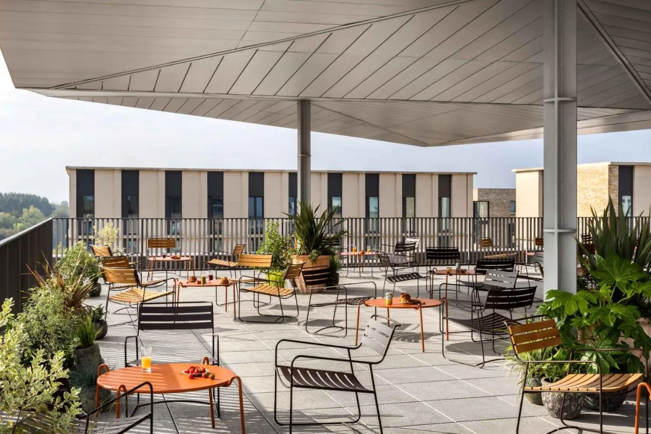 a patio with tables and chairs on a roof at Turing Locke Cambridge in Cambridge